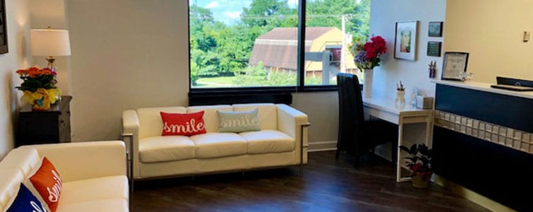 lobby at dentist office with white couches and pillows with the word smile on them